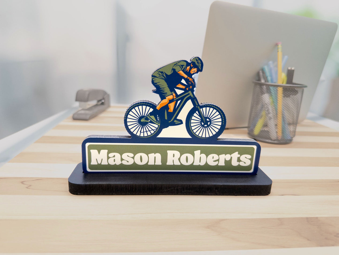 Side angle view of mountain biker desk sign with the name Mason Roberts on an office desk.
