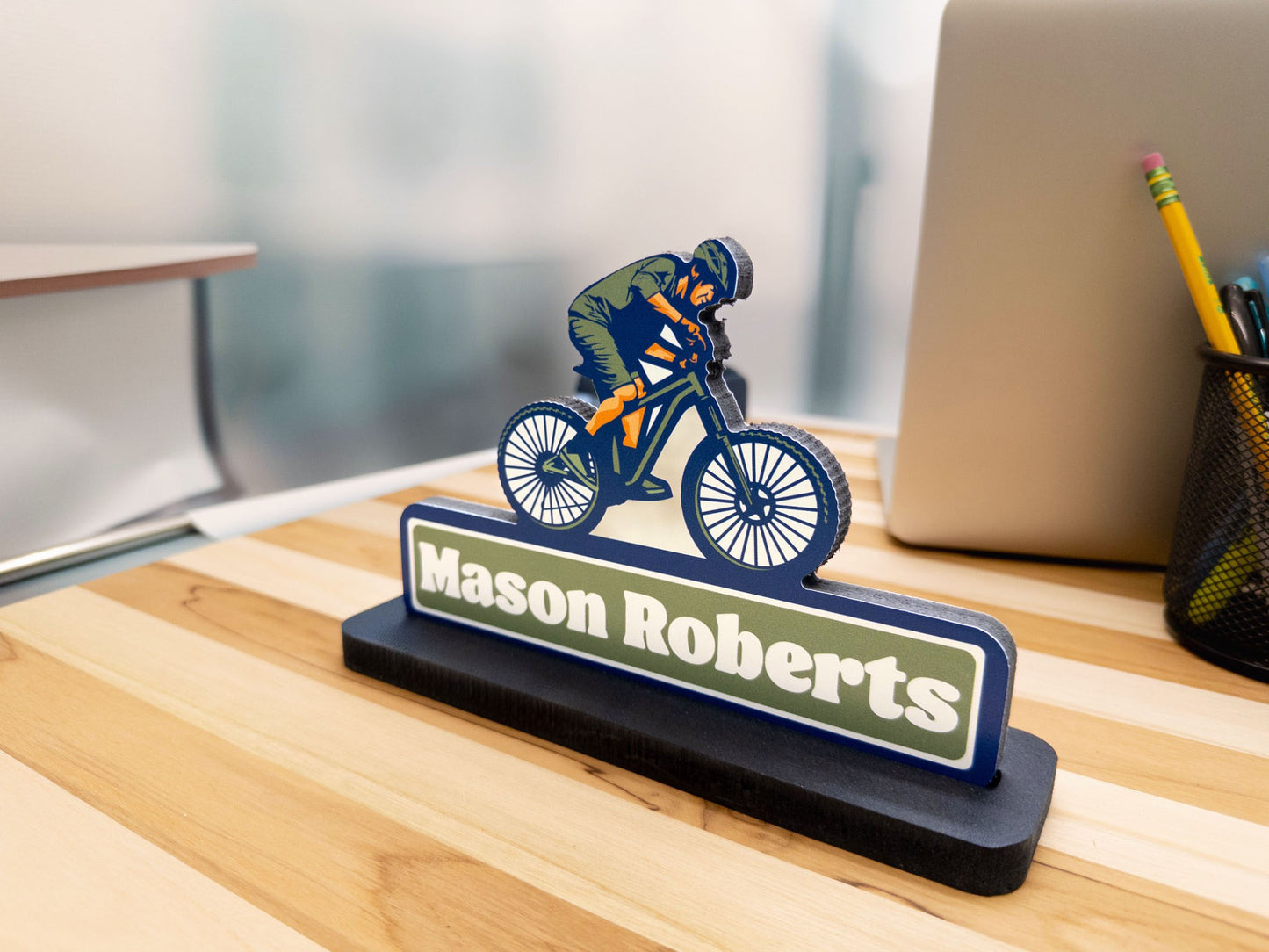 Side view of mountain biker desk sign with the name Mason Roberts on an office desk.