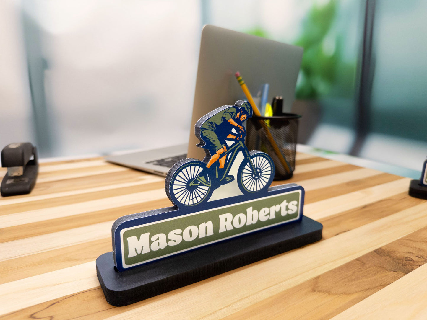 Mountain biker desk sign with the name Mason Roberts, front view with a laptop in the background.
