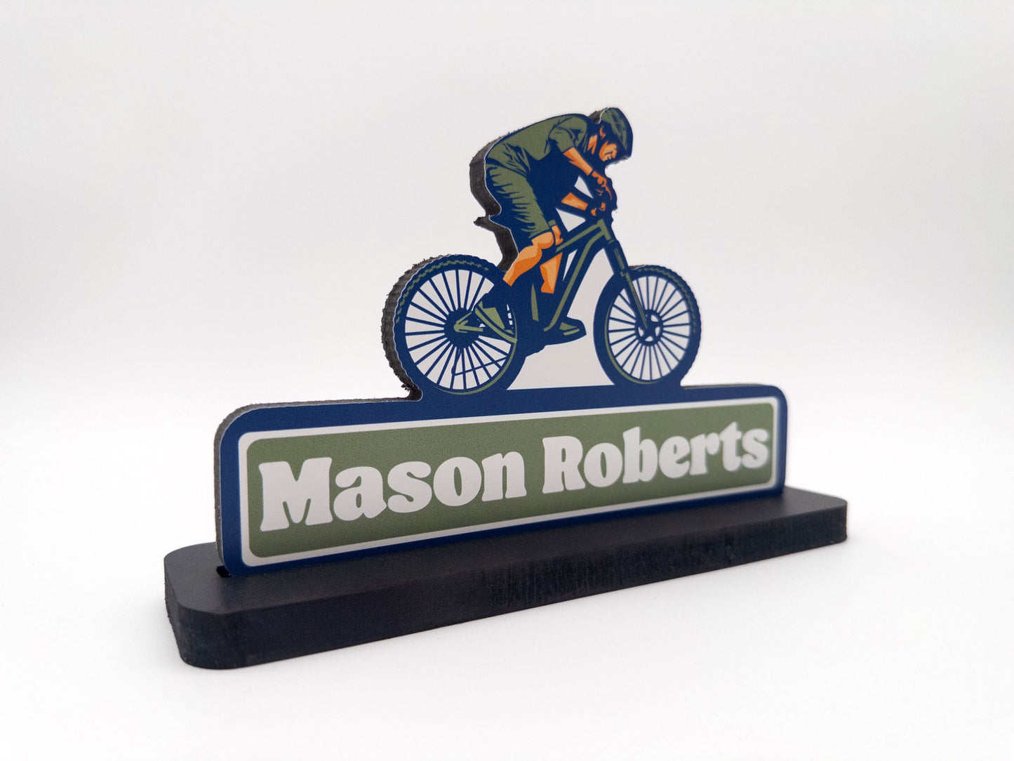 Side view of mountain biker desk sign with the name Mason Roberts against a white background.