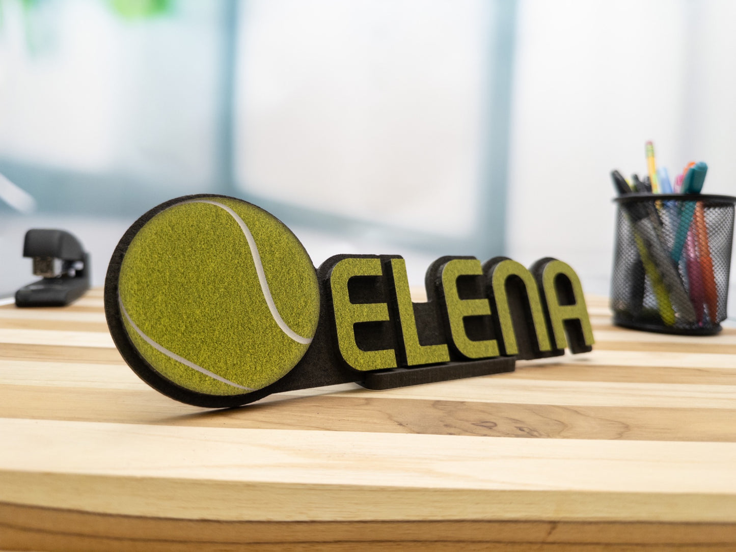 Angled view of a custom desk name plate showcasing the name 'Elena' with a tennis ball graphic, emphasizing its sporty appeal.