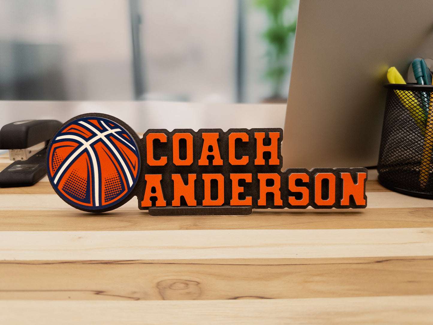 Basketball-themed desk sign for Coach Anderson, featuring a bold basketball graphic, placed on a wooden desk.