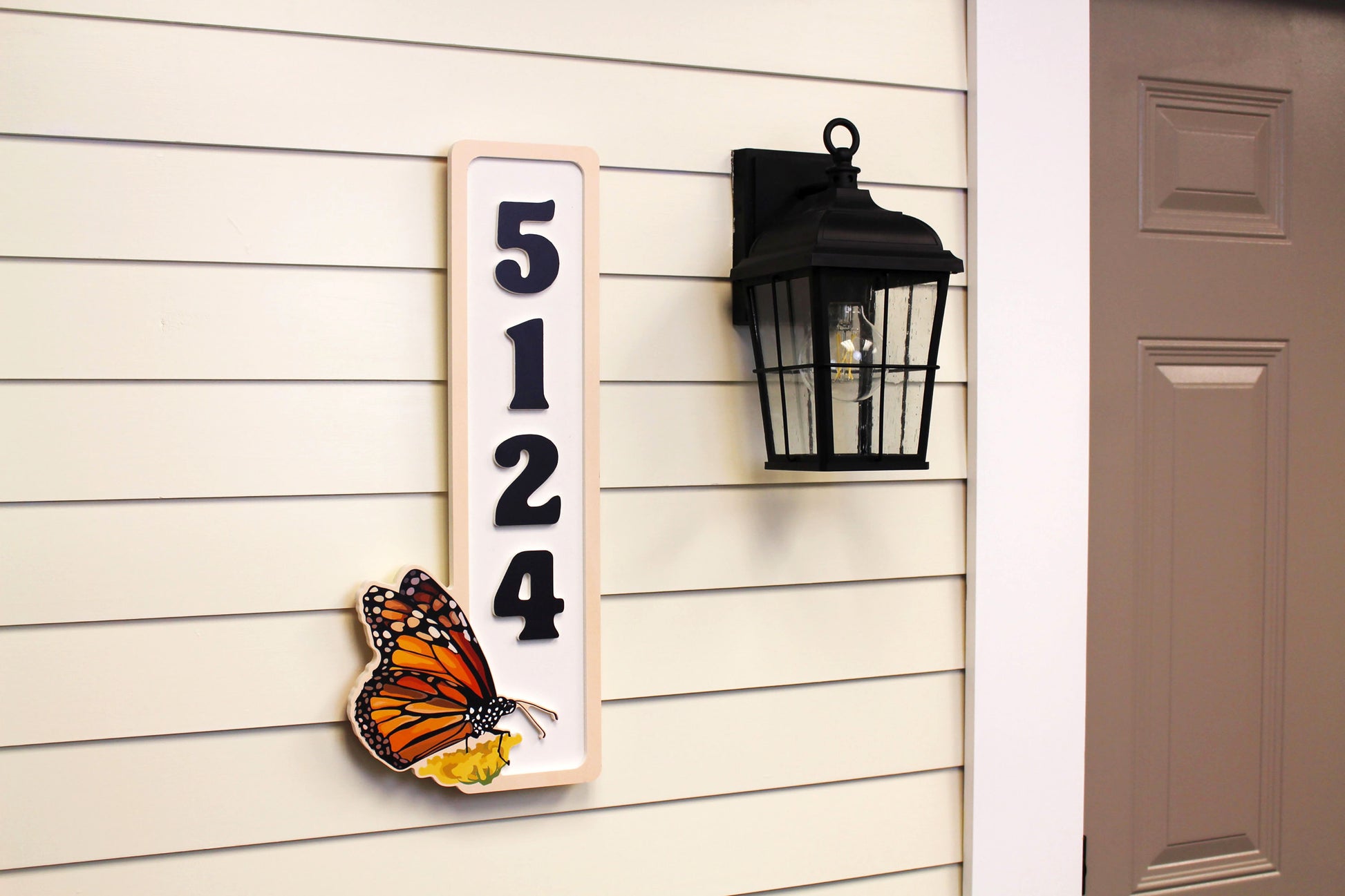 Vertical house number sign with a butterfly, shown from an angle to display the numbers and butterfly design.