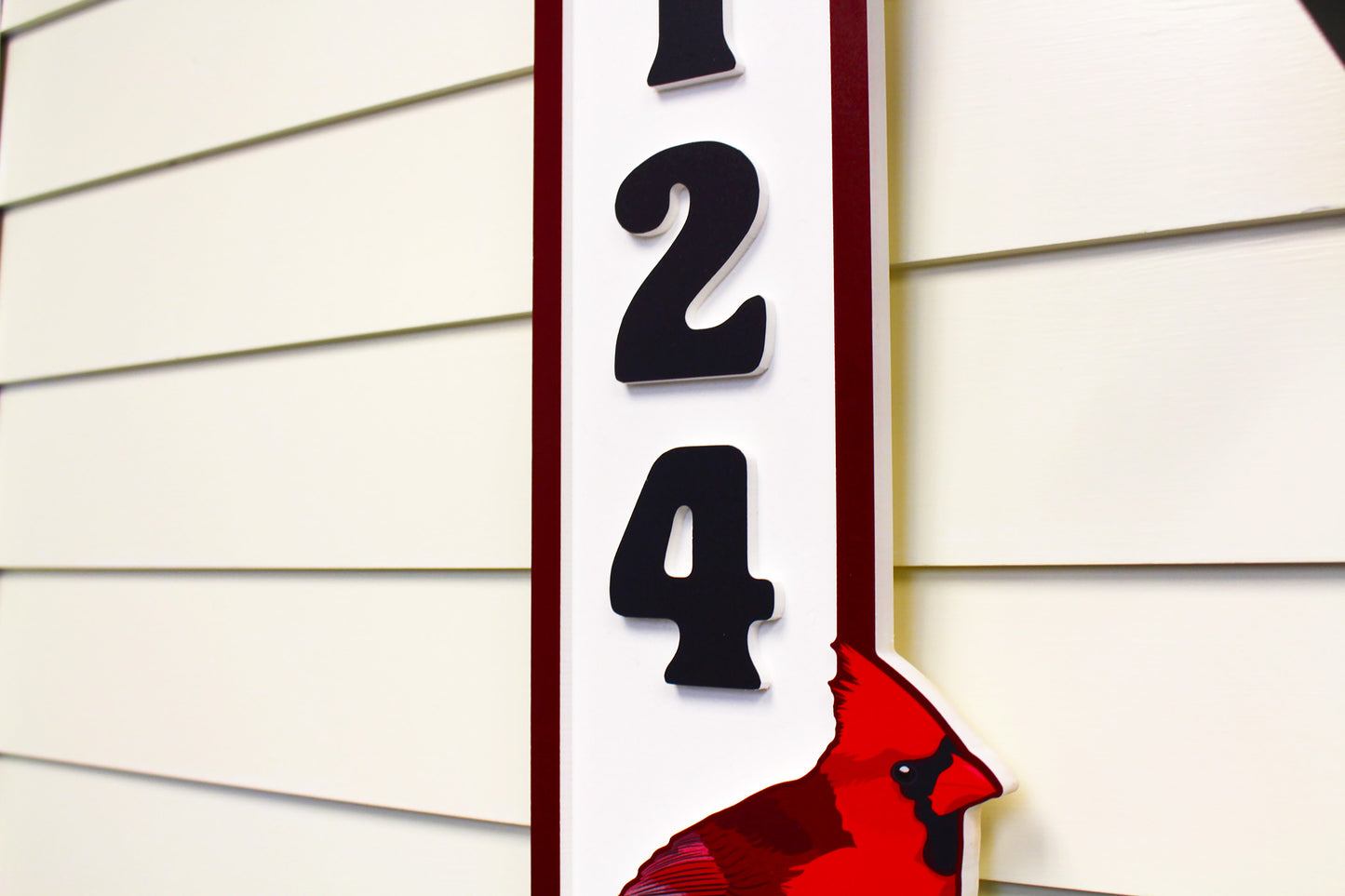 Detailed view of the red cardinal on a house number sign, showing intricate feather details on a white background.