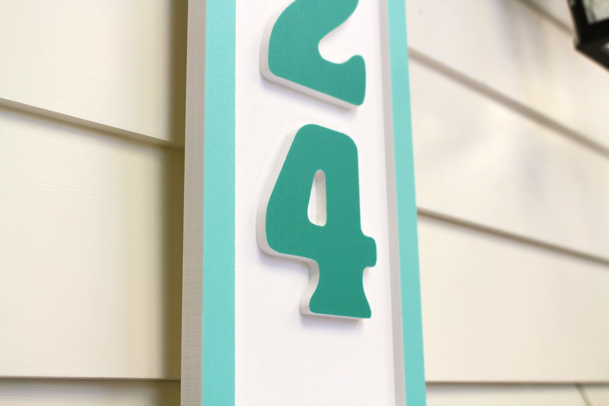 Close-up view of teal house number sign with the number "5124.