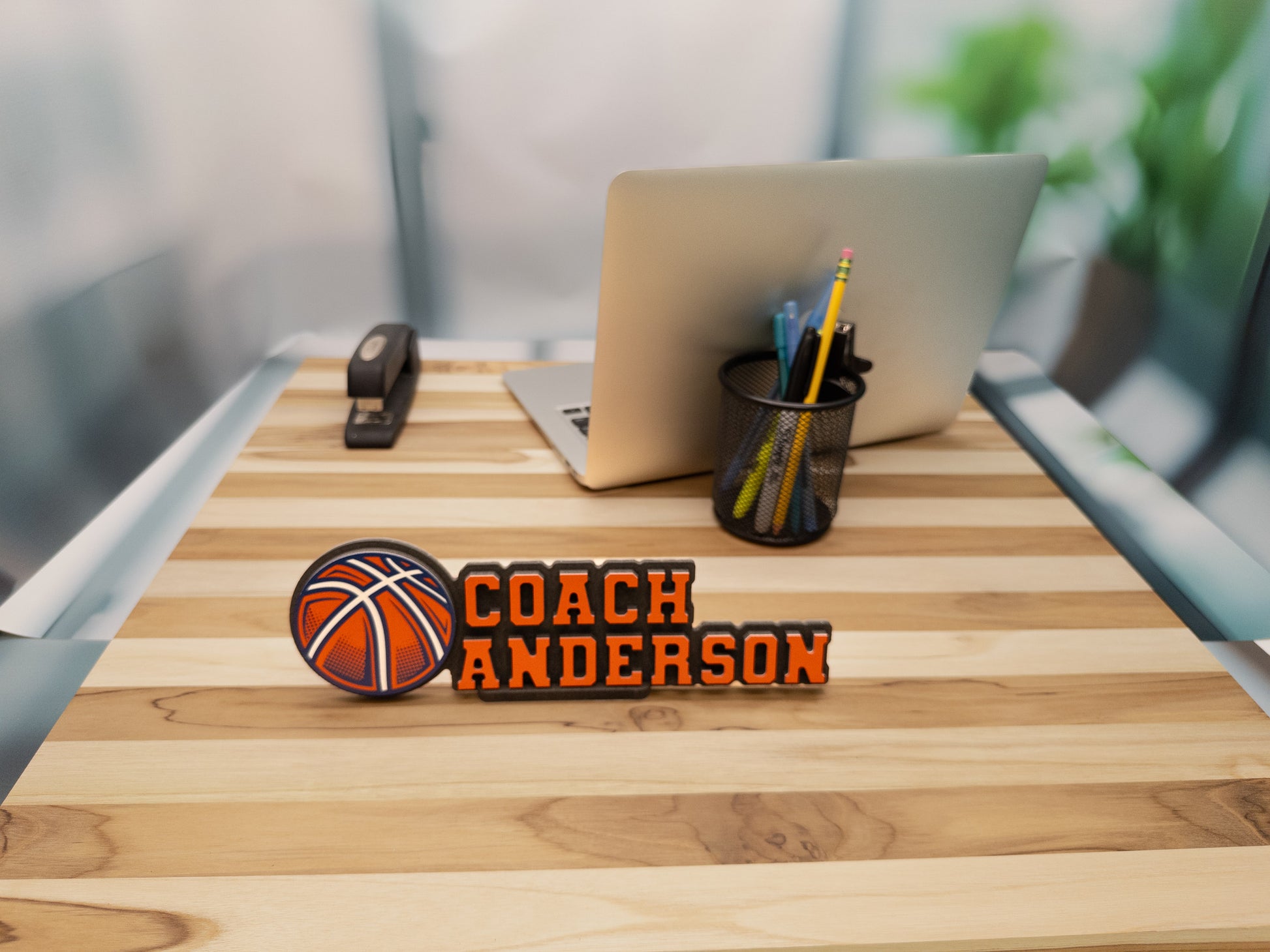 Basketball-themed desk name sign for Coach Anderson, featuring a large basketball illustration, shown in an office environment.