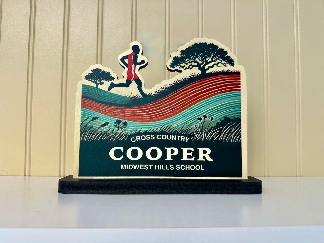 Custom cross country desk sign featuring a male runner silhouette on scenic background with tree and hills, labeled Cooper - Midwest Hills School.