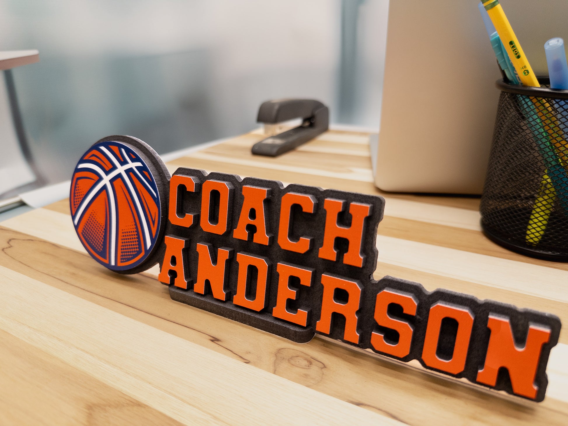 Desk name sign for Coach Anderson featuring a basketball design, displayed on an office desk.