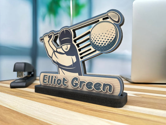 Desk name sign for Elliot Green featuring a golfer swinging a club with a golf ball, displayed on an office desk.