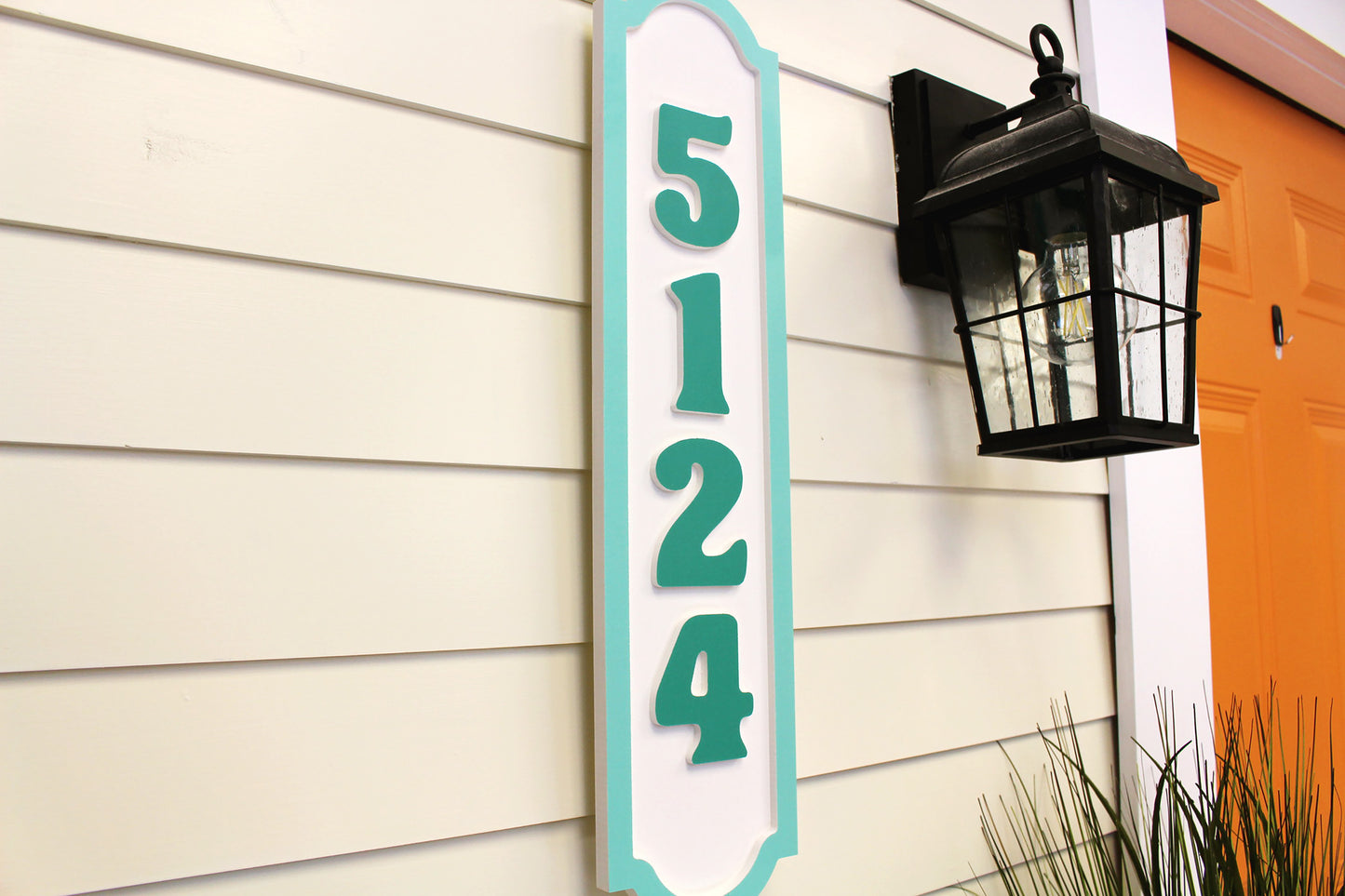 Side view of house number sign with teal border and raised numbers "5124.