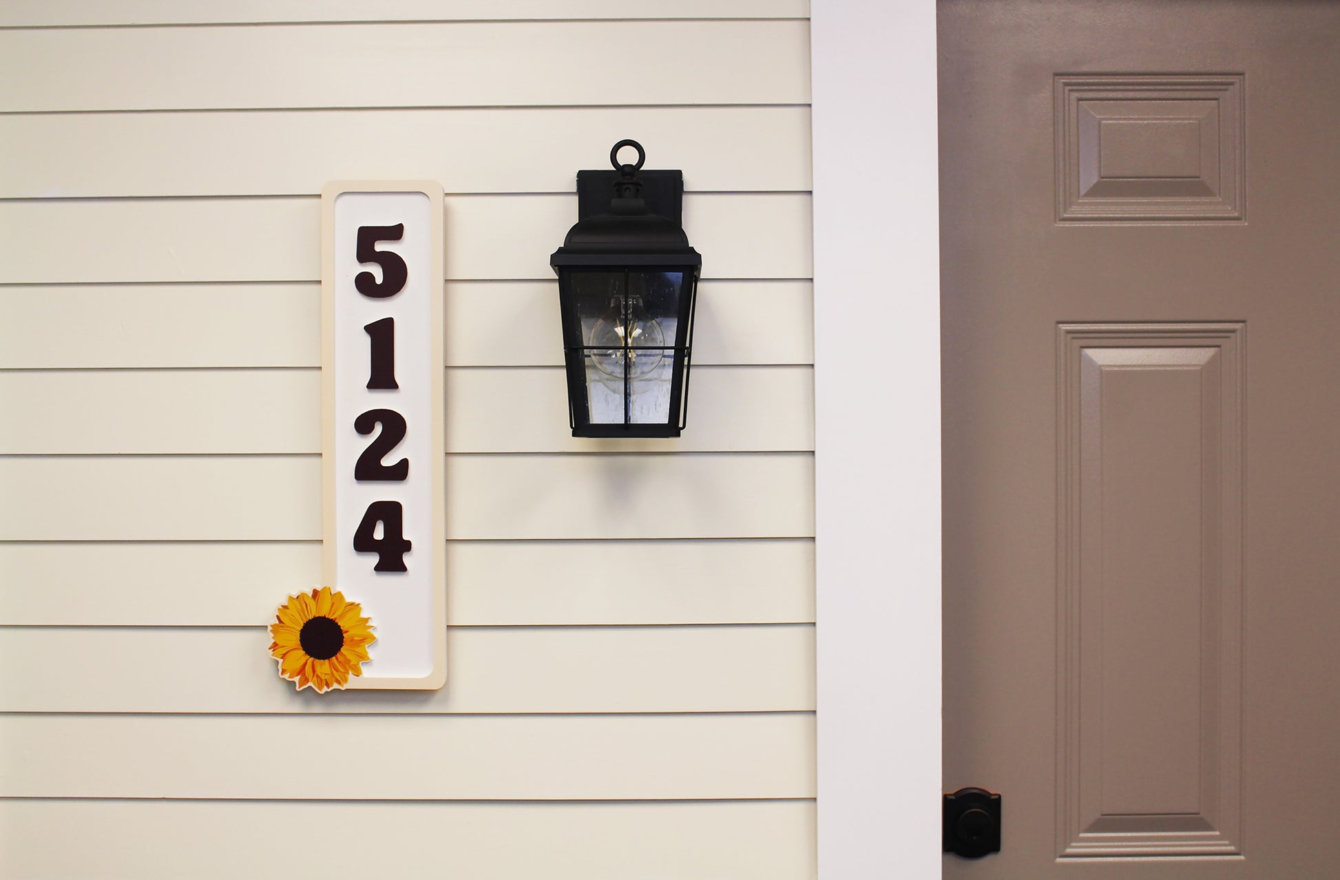 Full front view of house numbers sign with sunflower at the bottom.