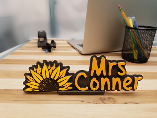 Personalized room sign with 'Mrs. Conner' and sunflower design on a striped wooden desk. Great for classroom decor or as a unique teacher gift.