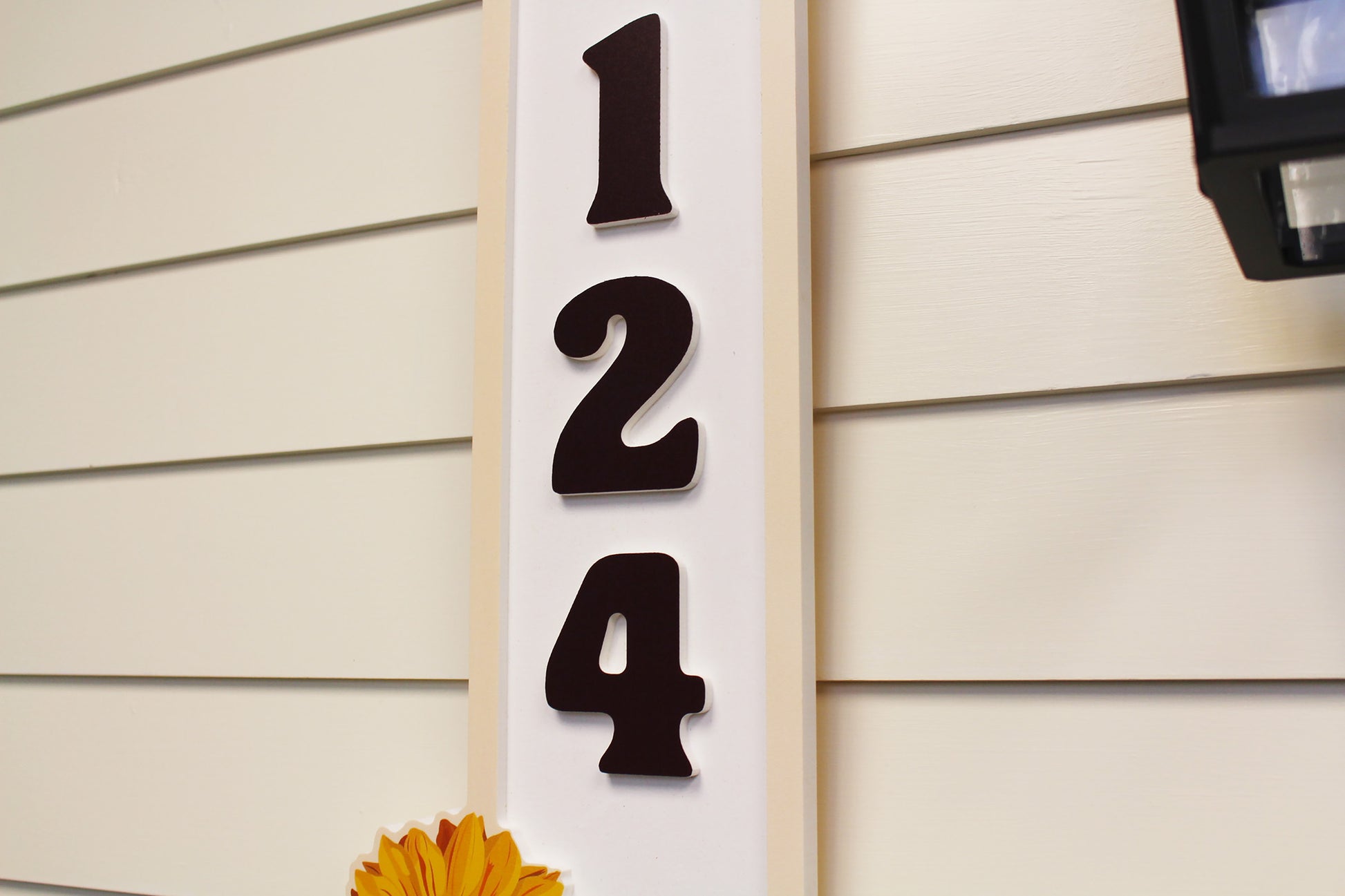 Angle close-up view of house numbers plaque with sunflower.