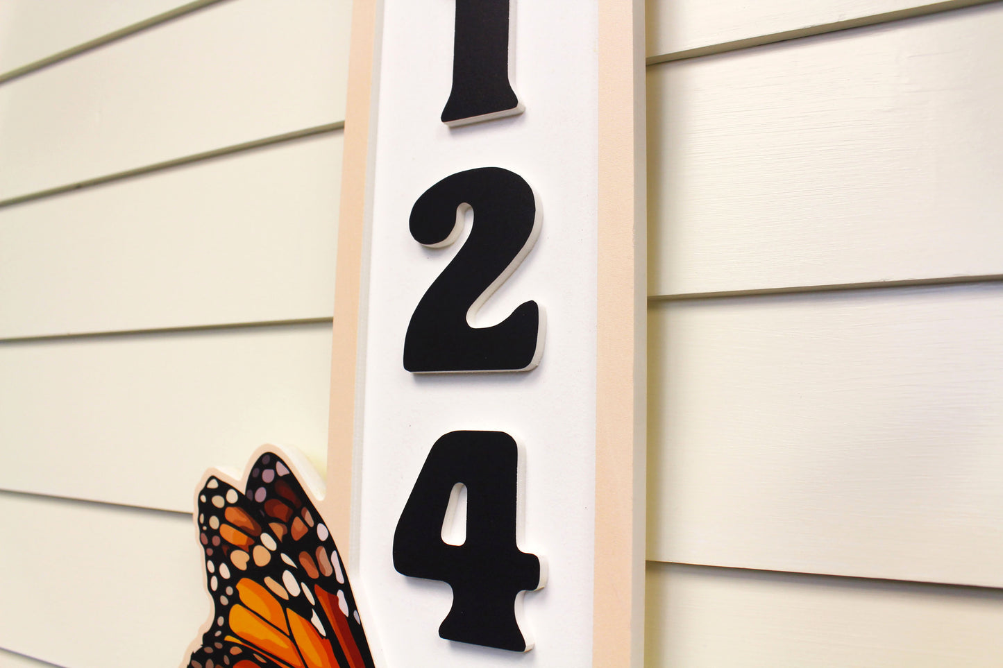 Close-up of a butterfly-themed vertical address sign showing the number 5124.